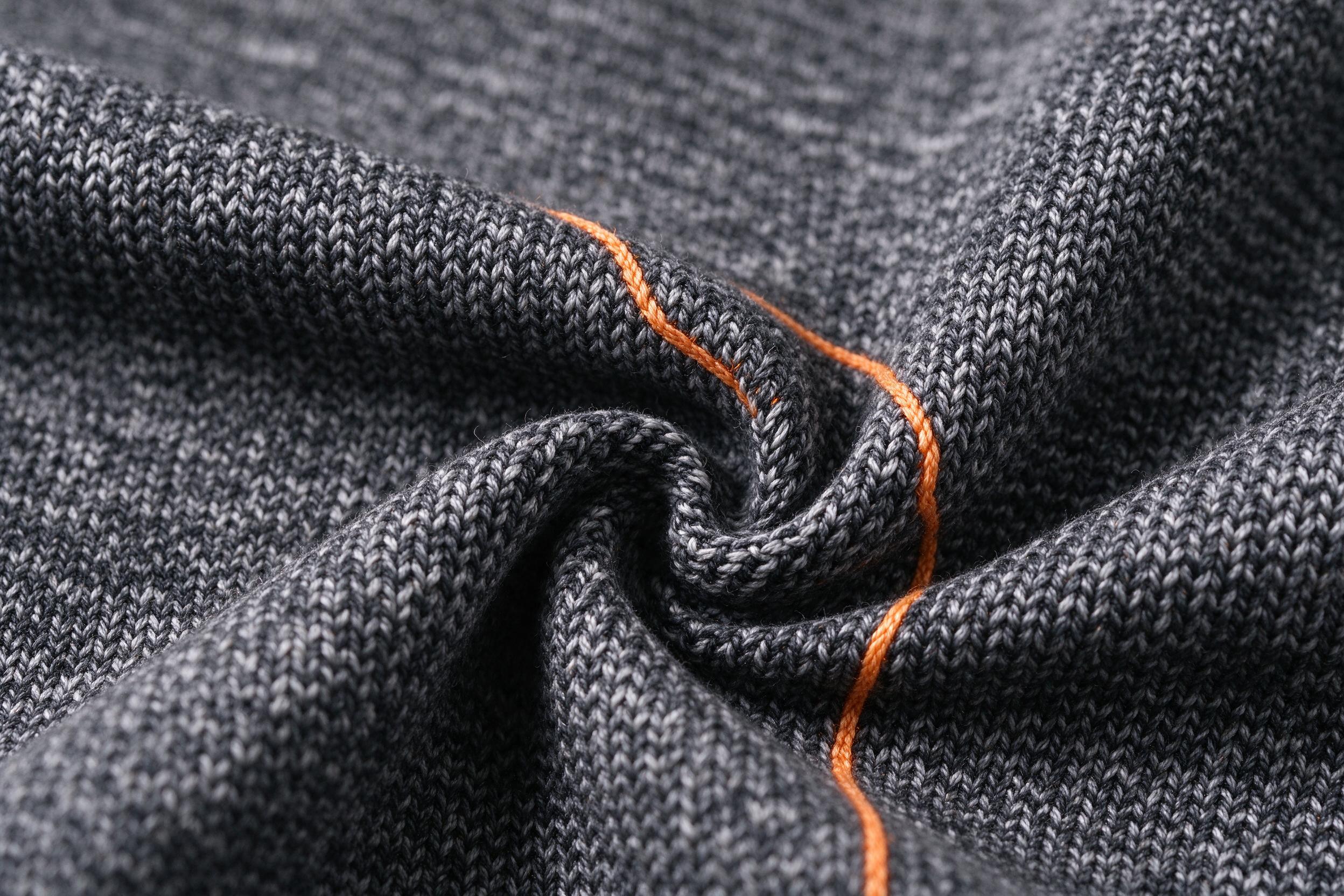 Close-up of dark performance knit fabric with orange stitch detail